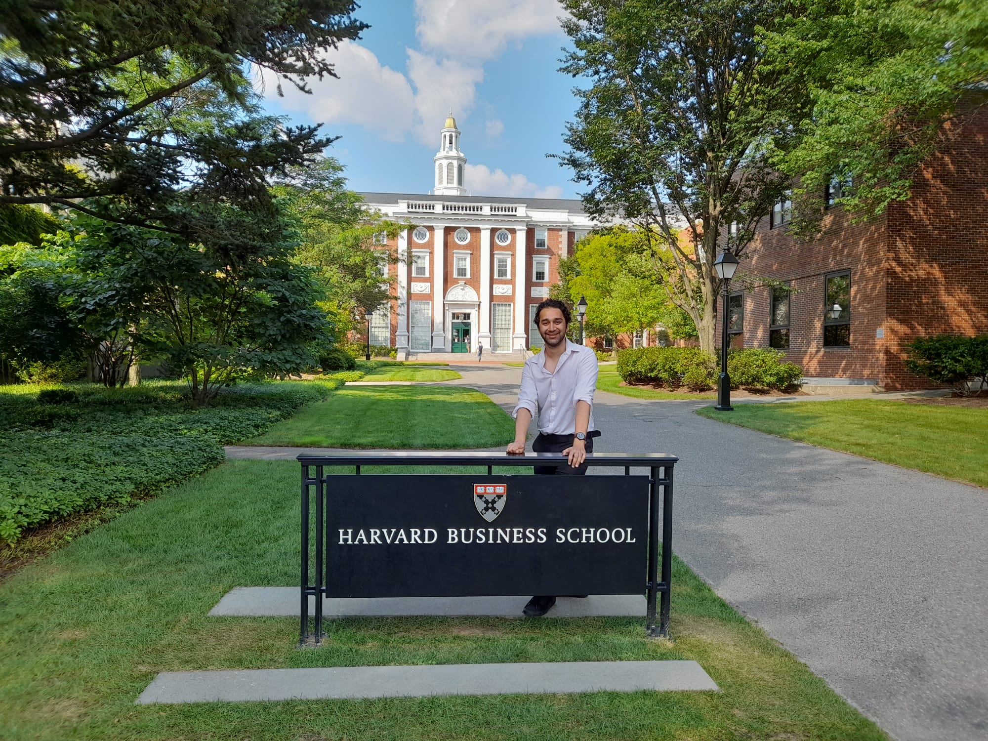 Deep Biswas standing beside the Harvard Business School sign on campus.